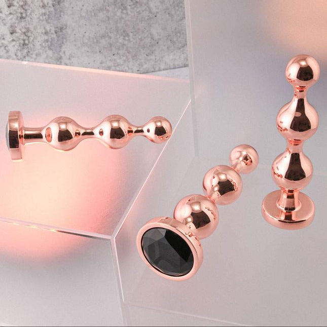 Gender X GOLD DIGGER Butt Plug Set laid down on stand with black gem